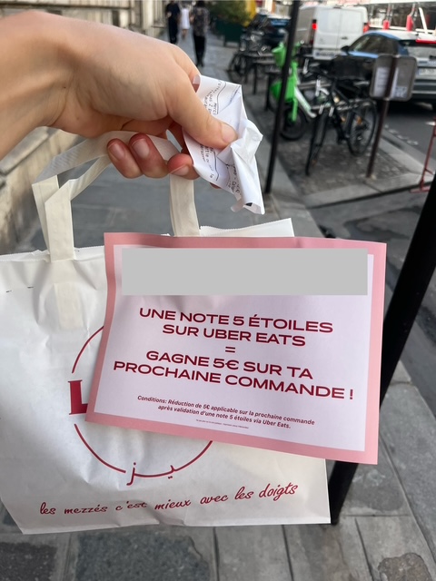 Carton agraphé sur une commande Uber Eats récupérée chez un traiteur où l’on est invité à laisser notre avis en échange de 5€ sur notre prochaine commande. 
