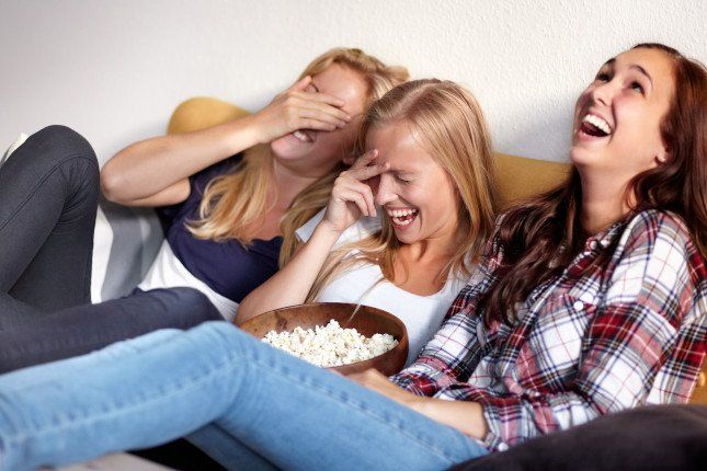 Trois amies profitant d’internet sans box à la maison, streaming et divertissement en ligne sur canapé.