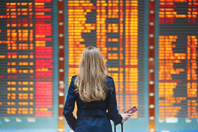 Voyageuse consultant les horaires de vol à l’aéroport, prête à utiliser une eSIM ou un Pass Voyage Orange à l’étranger