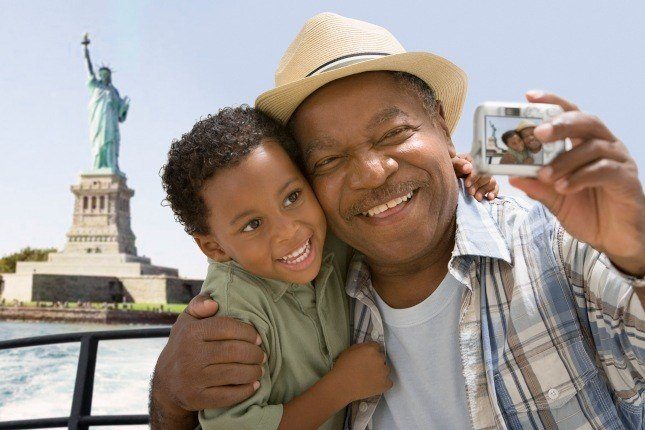 Un grand père et son petit fils devant la statue de la Liberté à New York