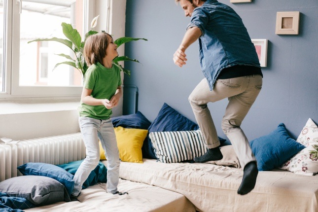 Photo d'un père et son fils sautant sur le canapé
