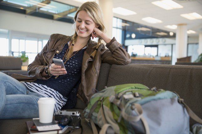 Jeune femme préparant sa valise et activant une eSIM sur tablette avant un voyage hors Europe