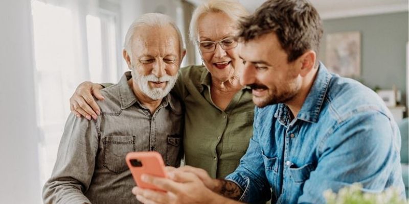 Famille aidant des seniors à utiliser un smartphone pour anticiper la fin de la 2G avec Orange