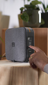 une main touche l'écran tactile de la Livebox 6 Orange pour faire apparaitre le QR code assistance facile